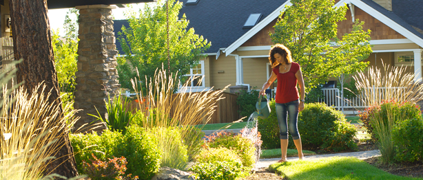 Woman in front of her house watering her plants
